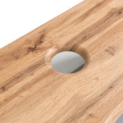 Nahaufnahme eines Waschtisch-Sets aus Holz mit natürlicher Maserung und einem runden Ausschnitt für das Waschbecken, aus der Vogelperspektive.