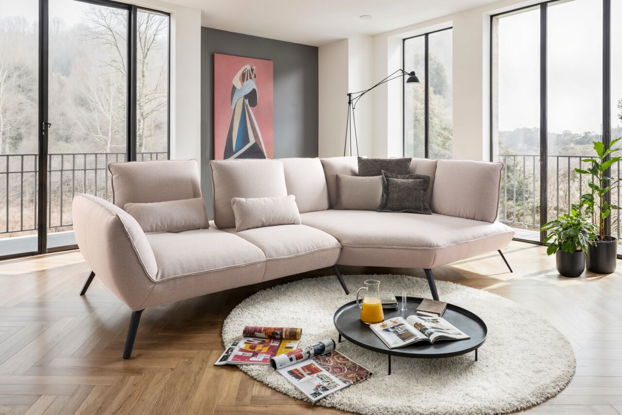 Beige Longchairkombination in modernem Wohnzimmer mit großen Fenstern, Kunstwerk an der Wand und Pflanzen, aus seitlicher Perspektive.