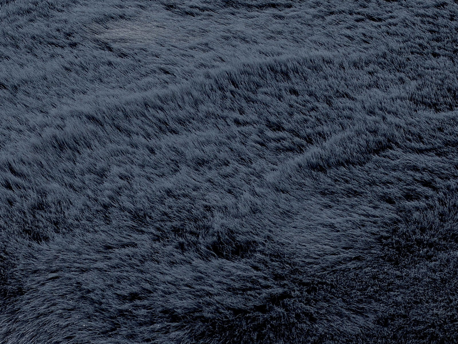 Nahaufnahme eines dunkelgrauen Fellteppichs mit weicher, flauschiger Textur.
