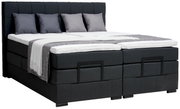 Boxspringbett in dunklem Stoffbezug mit vier Kissen und einer Decke, seitliche Perspektive