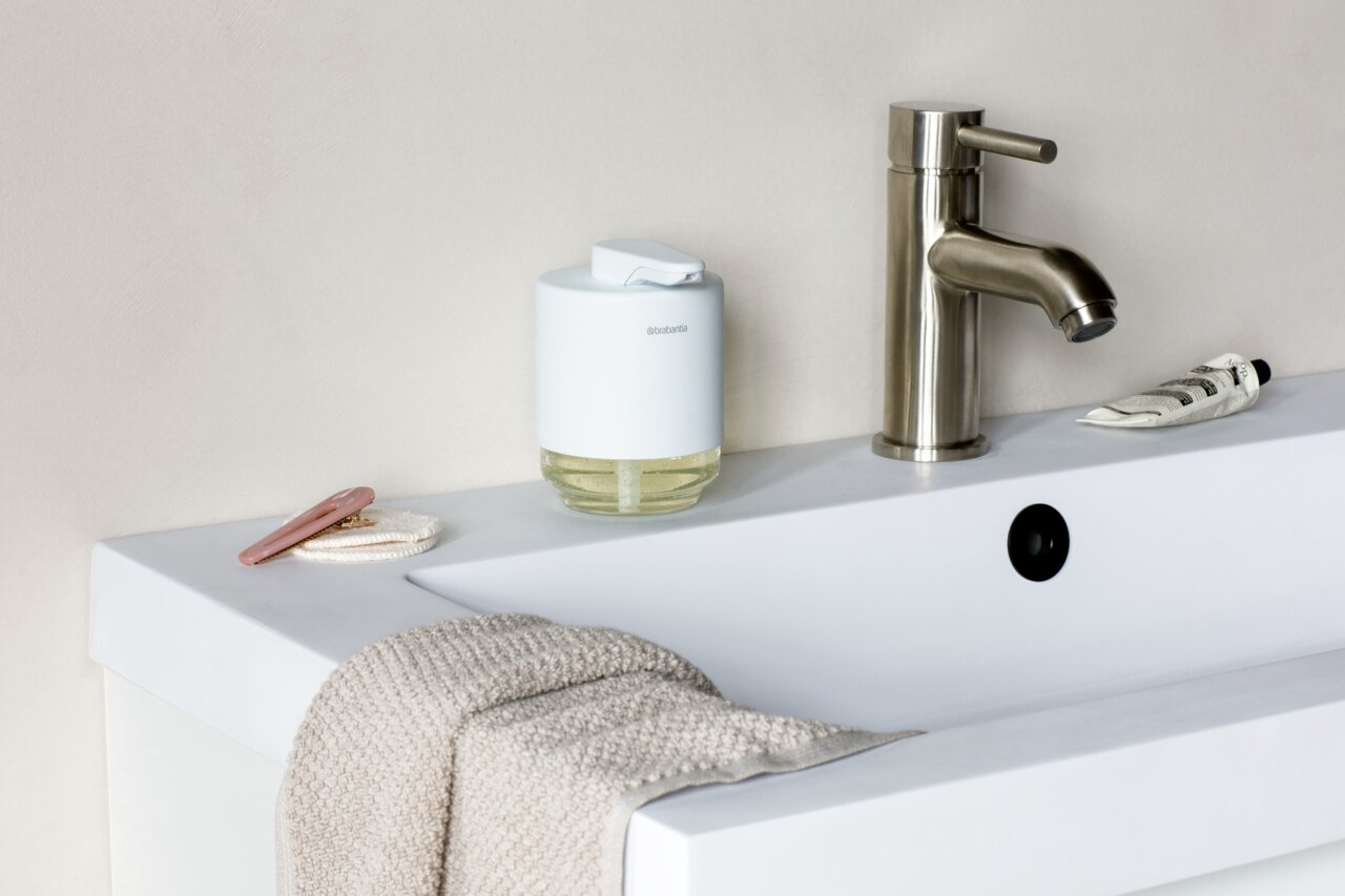 Brabantia Seifenspender MINDSET Moderner Seifenspender auf einem Waschbeckenrand, neben einem Wasserhahn, aus seitlicher Perspektive fotografiert.