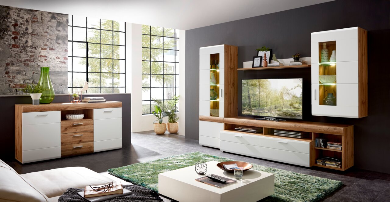 Moderne Wohnzimmermöbelkombination in Holzoptik mit weißen Fronten, bestehend aus Sideboard, TV-Schrank und Vitrinen, seitliche Perspektive.
