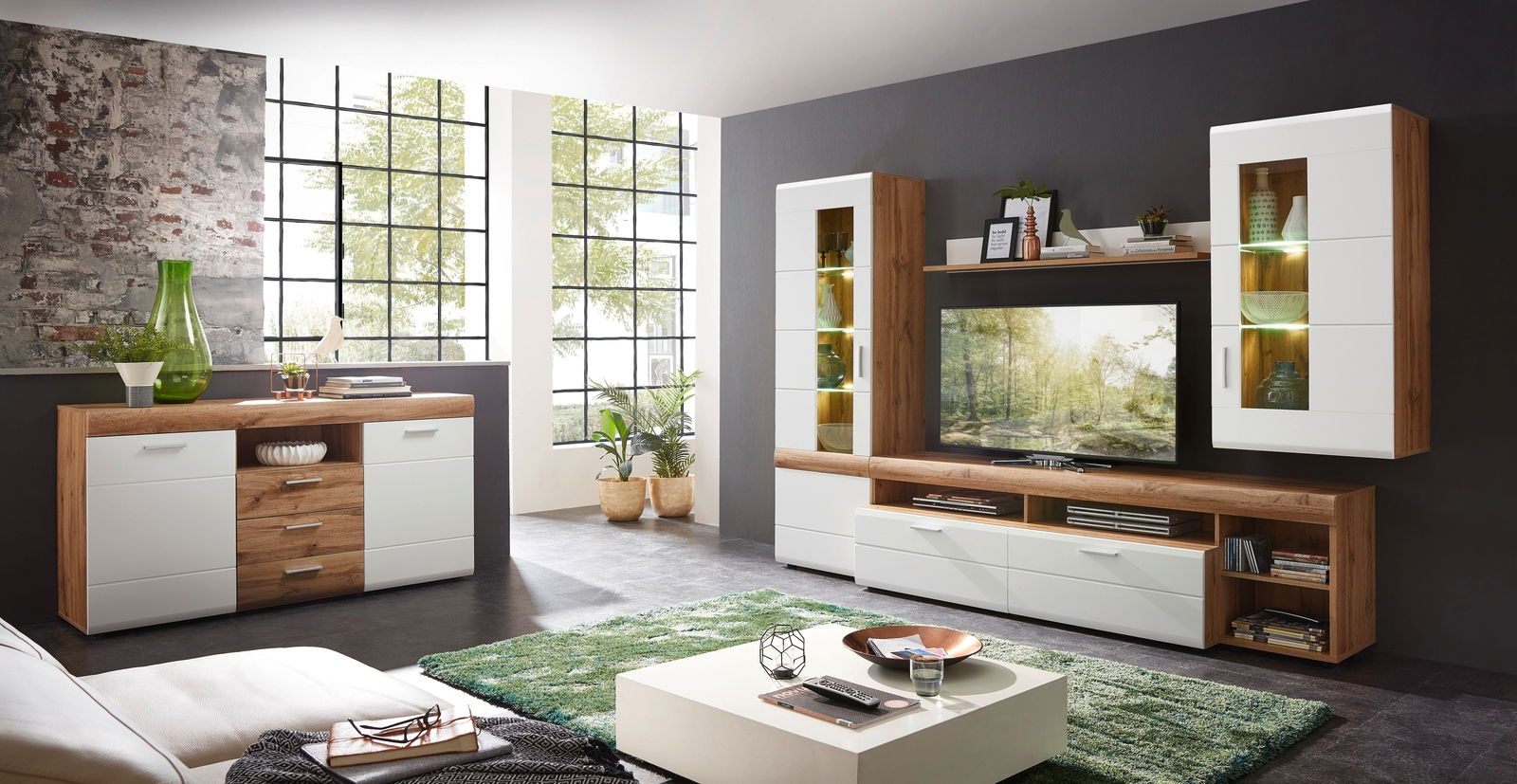 Moderne Wohnzimmermöbelkombination in Holzoptik mit weißen Fronten, bestehend aus Sideboard, TV-Schrank und Vitrinen, seitliche Perspektive.