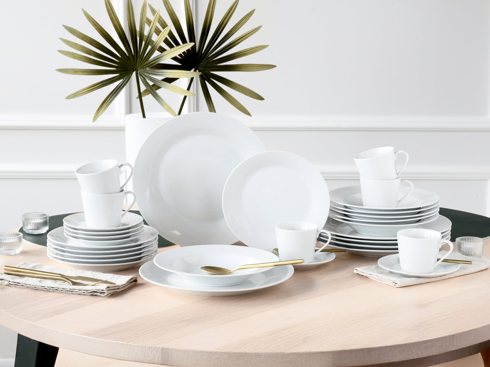 creaTable Kombiservice 30-tlg BASE Weißes Porzellan-Geschirrset mit Tellern, Schalen und Tassen auf einem gedeckten Holztisch, frontal in leichter Aufsicht fotografiert.