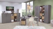 Moderne Büroumgebung mit grauem Schreibtisch, Rollcontainer und Aktenschränken in Holzoptik, seitliche Perspektive.