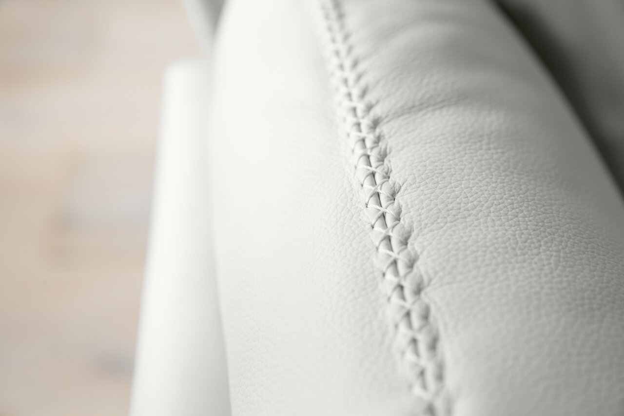 Nahaufnahme einer weißen Polsterrundecke mit feiner Naht, seitliche Perspektive