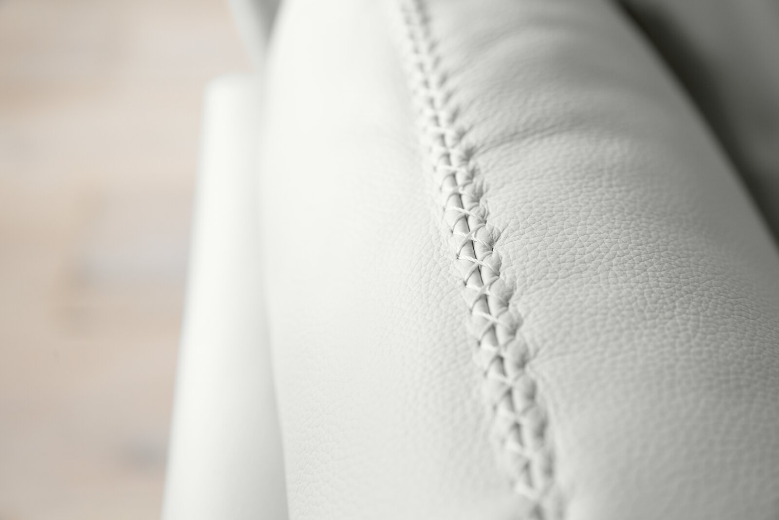 Nahaufnahme einer weißen Polsterrundecke mit feiner Naht, seitliche Perspektive