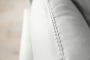 Nahaufnahme einer weißen Polsterrundecke mit feiner Naht, seitliche Perspektive
