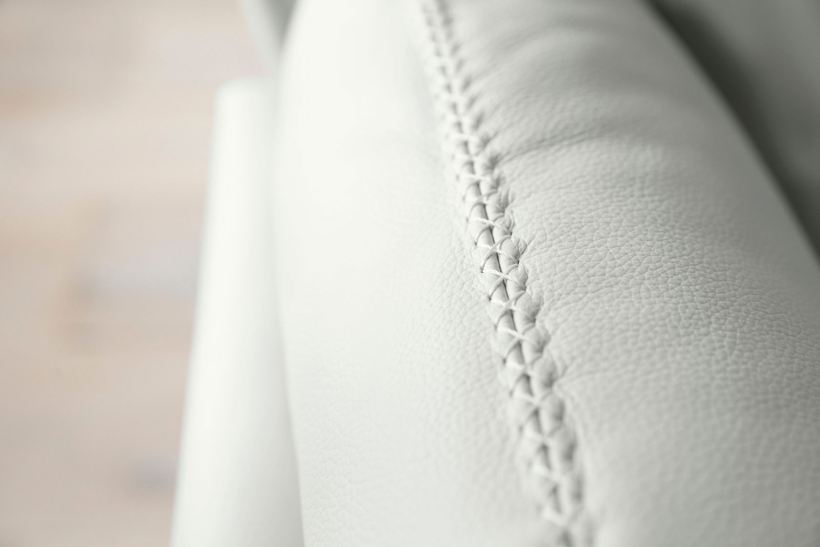 Nahaufnahme einer weißen Polsterrundecke mit feiner Naht, seitliche Perspektive