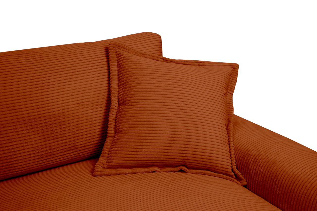 Nahaufnahme eines Big-Sofas in warmem Terrakotta-Ton mit geripptem Stoffbezug und passendem Kissen, seitliche Perspektive.