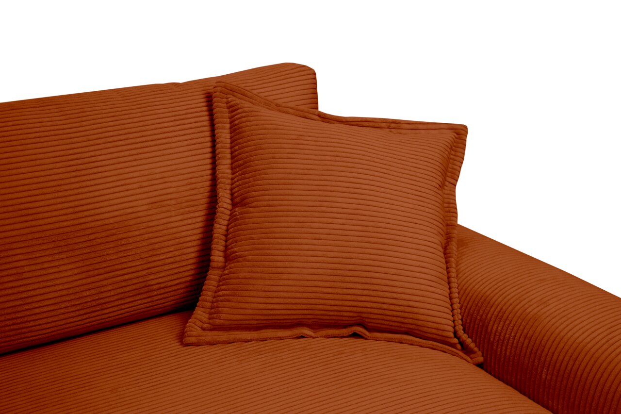 Nahaufnahme eines Big-Sofas in warmem Terrakotta-Ton mit geripptem Stoffbezug und passendem Kissen, seitliche Perspektive.