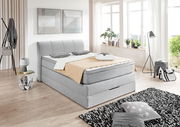 Graues Boxspringbett in modernem Schlafzimmer, seitliche Perspektive