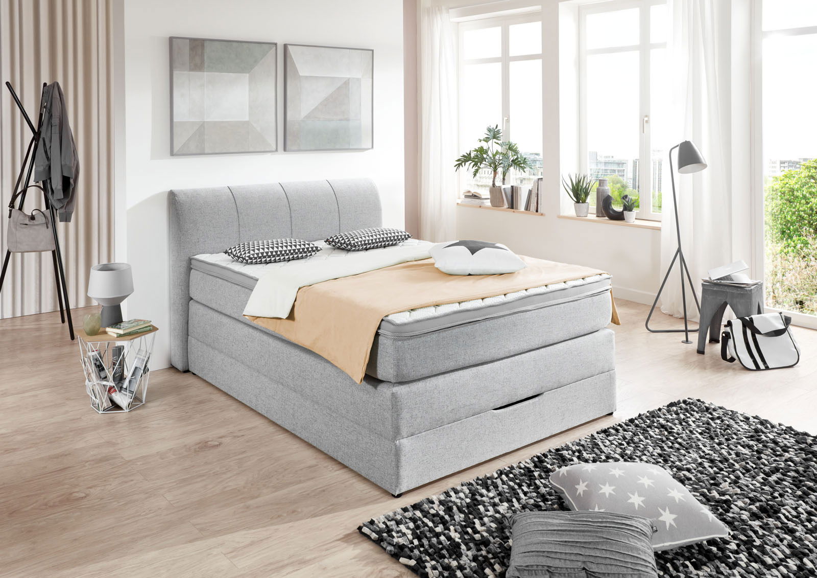 Graues Boxspringbett in modernem Schlafzimmer, seitliche Perspektive