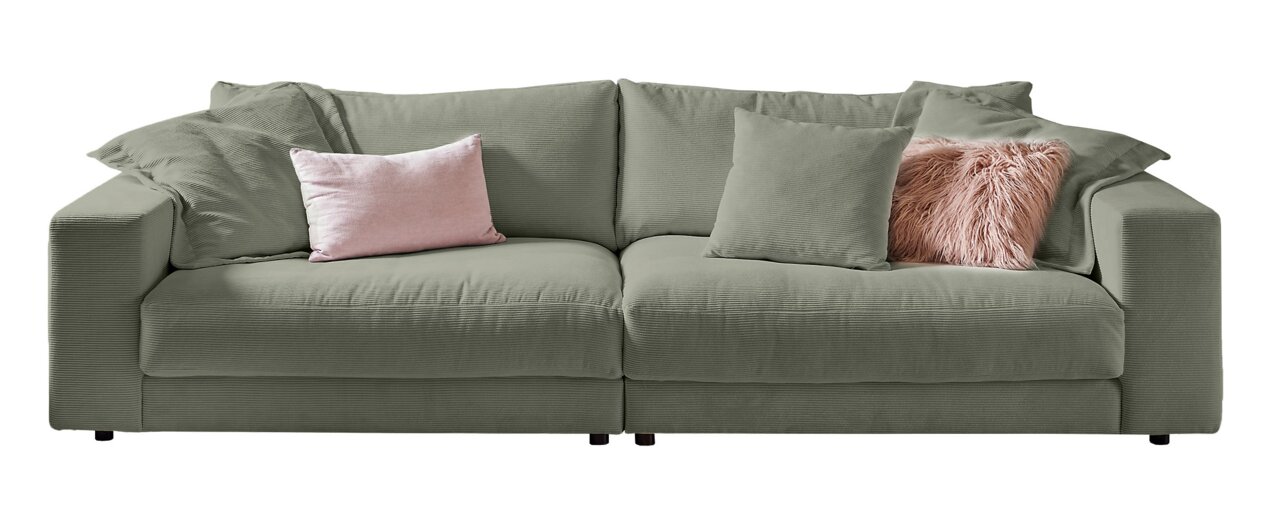 Lounge Handmade Big Sofa LH-SAMBIA Großes, grünes Sofa mit mehreren Kissen, darunter ein rosa und ein flauschiges Kissen, aus frontaler Perspektive.