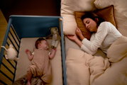 Een opklapbed naast een bed waarin een baby en een vrouw slapen, gezien vanuit vogelperspectief.