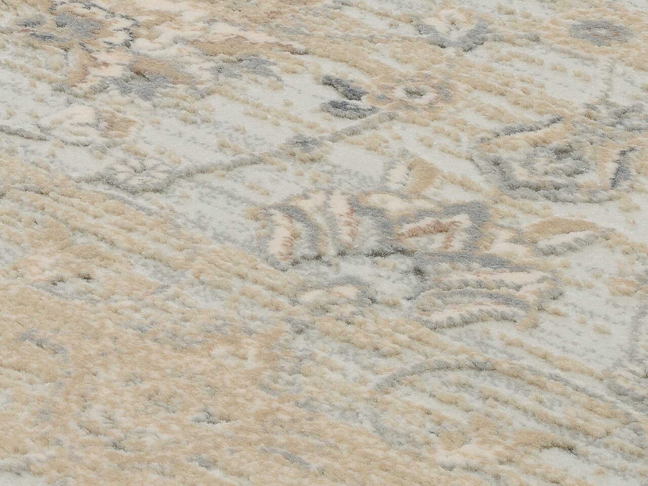 Nahaufnahme eines Designer Teppichs mit abstraktem Muster in Beige- und Grautönen, von oben betrachtet.