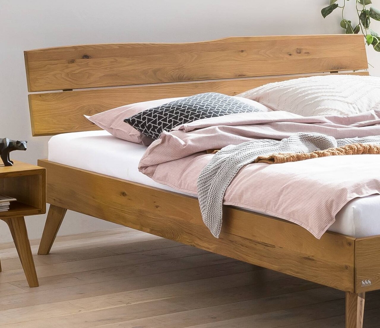 Holzbettgestell mit Kopfteil aus Holz, seitliche Perspektive, dekoriert mit Kissen und Decken