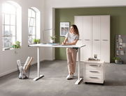 Elektrisch höhenverstellbarer Schreibtisch in einem modernen Büro mit einer Frau, die daran arbeitet. Perspektive von vorne.