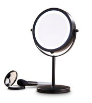 Schwarzer Schminkspiegel mit Beleuchtung, aufrecht stehend, mit einem Pinsel und einem kleinen runden Spiegel im Vordergrund.