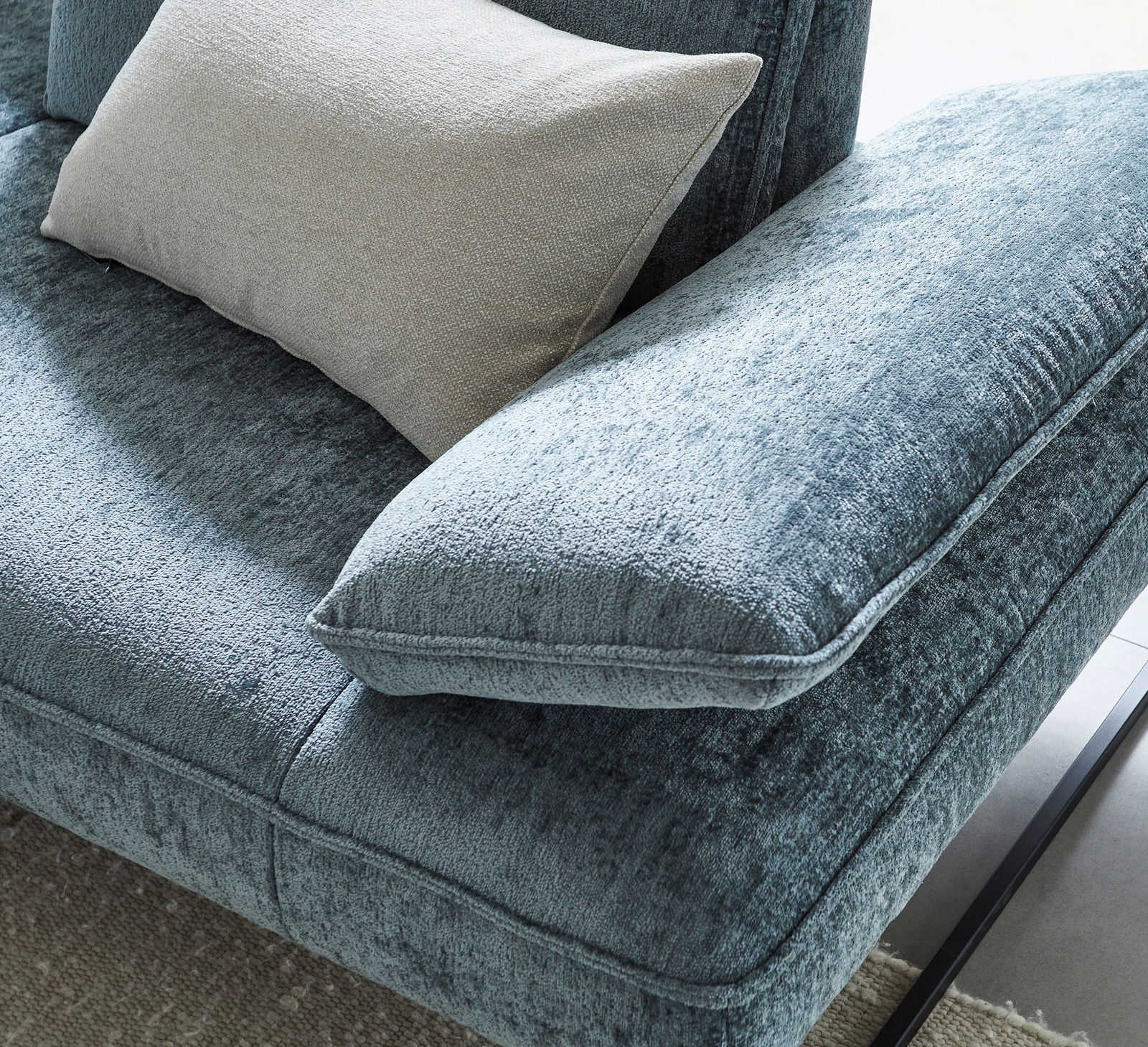 Nahaufnahme einer blauen Longchairkombination mit weichem Stoffbezug und einem beigen Kissen, von oben betrachtet.