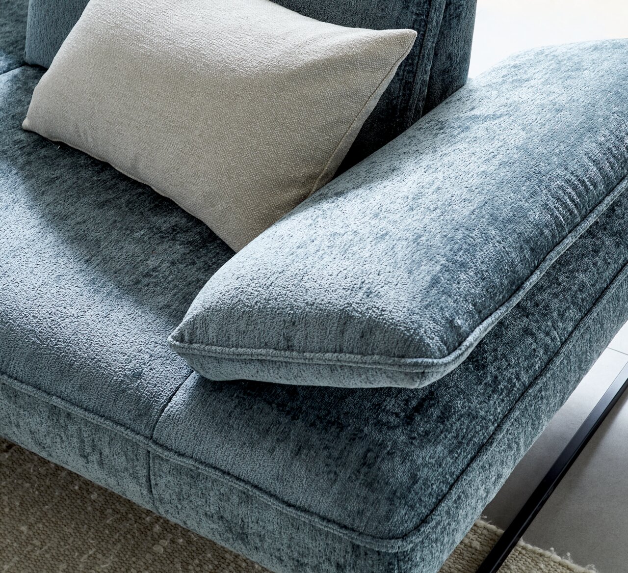 Close-up van een blauwe ligstoelcombinatie met een zachte stoffen bekleding en een beige kussen, gezien van bovenaf.