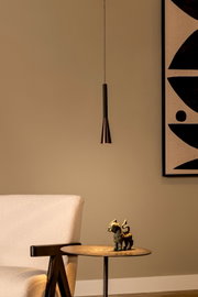 Minimalistische schwarze Pendelleuchte mit schlankem zylindrischem Körper und konischem Metallschirm über einem runden Beistelltisch, frontale Innenraumansicht
