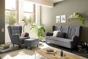 Wohnzimmer mit grauem Sessel, Hocker und Sofa in moderner Einrichtung, seitliche Perspektive