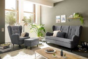 Wohnzimmer mit grauem Sessel, Hocker und Sofa in moderner Einrichtung, seitliche Perspektive