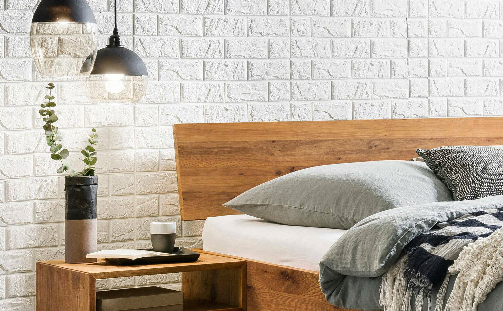 Holzbettgestell mit Kopfteil aus Holz, seitliche Perspektive, dekoriert mit Kissen und Decke, daneben ein Nachttisch mit Vase und Lampe