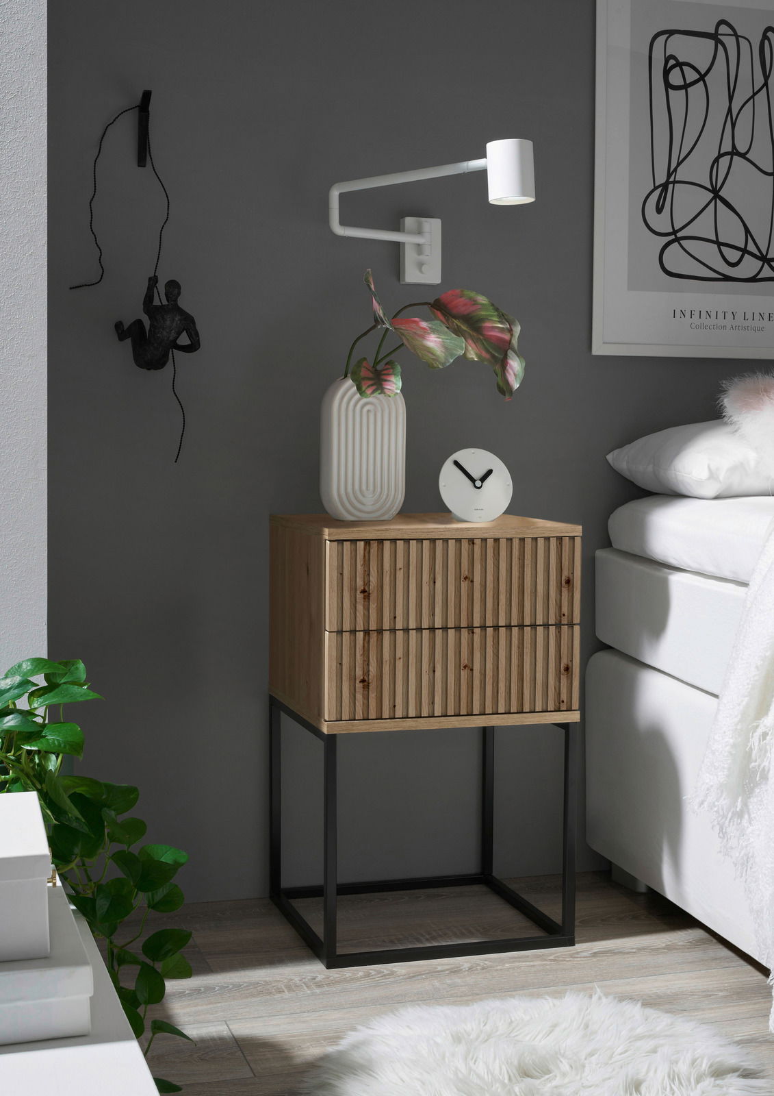 Moderne Nachtkommode aus Holz mit gerillter Front und schwarzem Metallgestell, seitliche Perspektive, dekoriert mit einer Vase und einer Uhr.