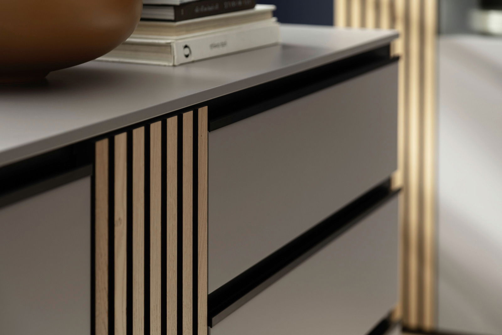 Nahaufnahme eines modernen Sideboards mit Holzlamellen und glatten Schubladenfronten, seitliche Perspektive