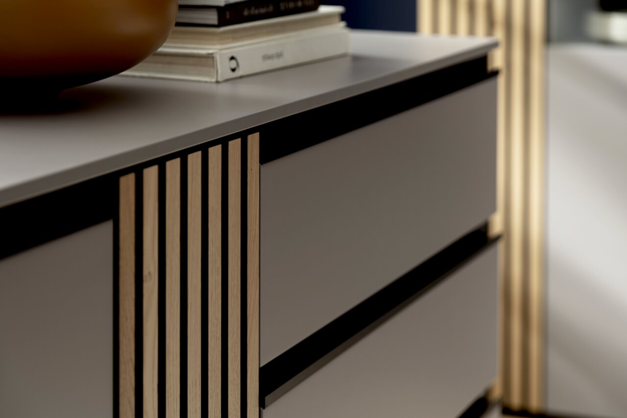 Nahaufnahme eines modernen Sideboards mit Holzlamellen und glatten Schubladenfronten, seitliche Perspektive