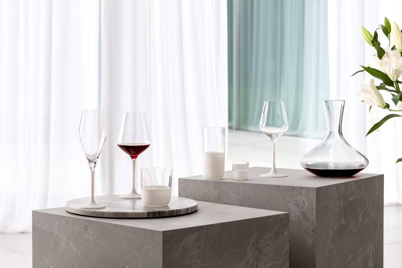 Elegantes Rotweinglas-Set mit modernem Design, präsentiert auf einem stilvollen Podest in einem hellen, minimalistischen Raum. Seitliche Perspektive.