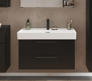 Frontale Ansicht eines modernen Waschtisch-Sets mit weißem Waschbecken und schwarzem Unterschrank, ausgestattet mit einem schwarzen Wasserhahn und Accessoires.