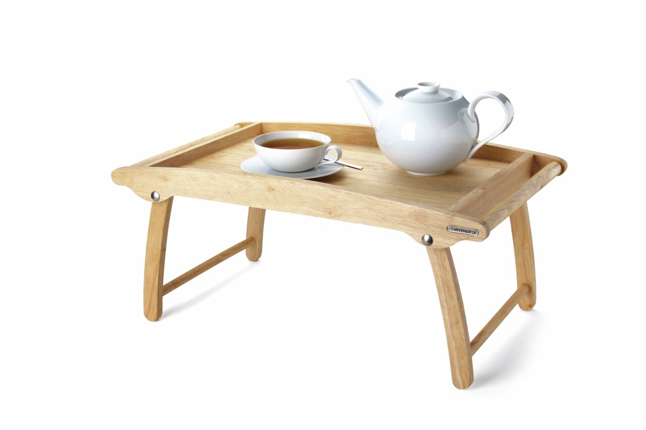 Holz-Betttablett mit hochgeklappten Beinen, darauf eine weiße Teekanne und Tasse, seitliche Perspektive