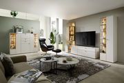 Moderne Wohnzimmeransicht mit eleganter Vitrine, die von vorne gezeigt wird, neben einem großen Fernseher und stilvollen Möbeln.