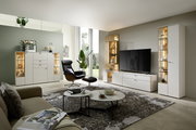 Moderne Wohnzimmeransicht mit eleganter Vitrine, die von vorne gezeigt wird, neben einem großen Fernseher und stilvollen Möbeln.