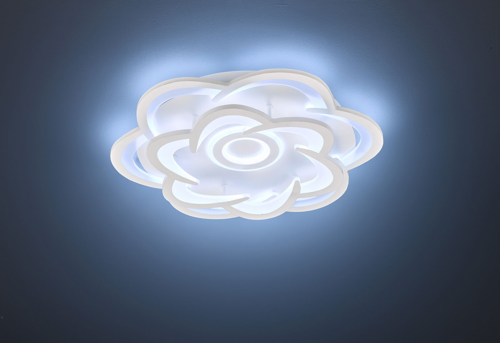 Moderne LED-Deckenleuchte in Blumenform, von unten betrachtet, mit sanftem blauem Lichtschein an der Decke.