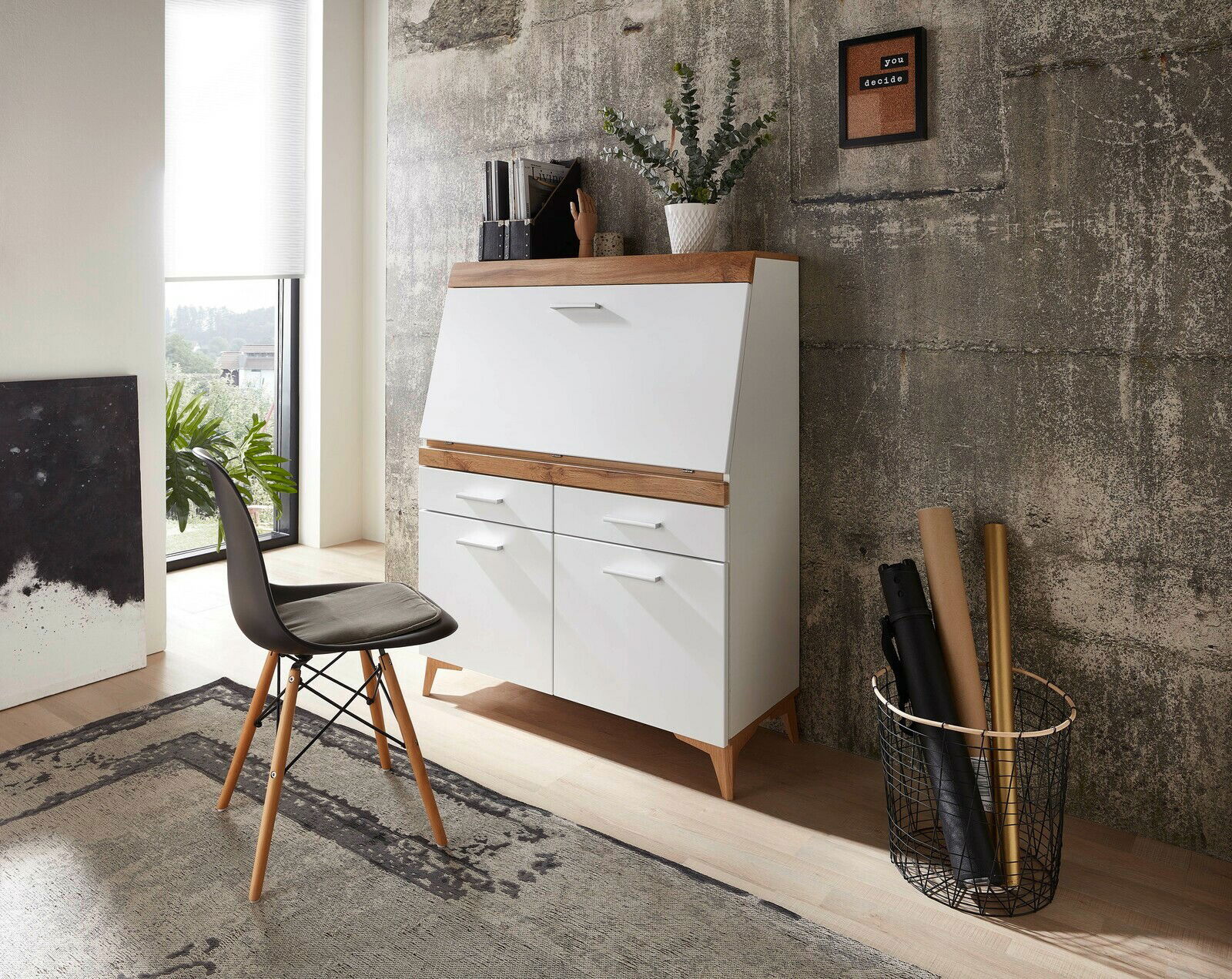 Moderner Sekretär in Weiß mit Holzdetails, seitliche Perspektive, umgeben von Dekorationen und einem Stuhl.