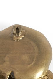 Nahaufnahme eines goldfarbenen Wandornaments mit Aufhängung, Rückansicht