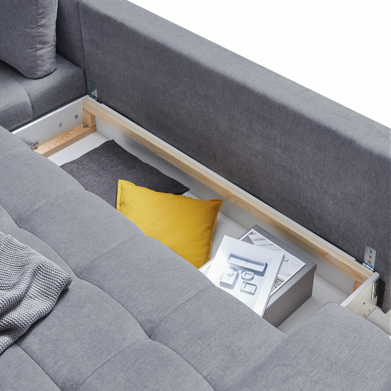 Graue Rundecke FIGARO mit Stauraum, von oben betrachtet, zeigt Kissen und Zeitschriften im offenen Fach.