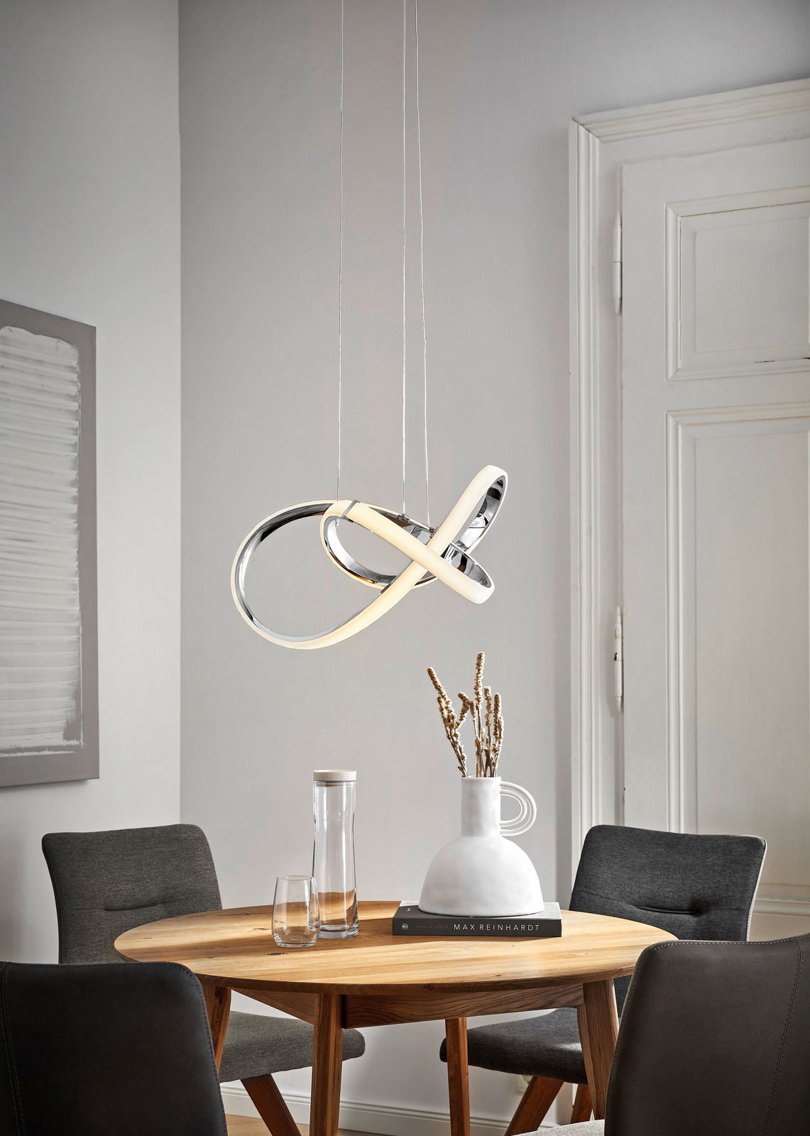 Moderne LED-Pendelleuchte in geschwungenem Design über einem Esstisch, seitliche Perspektive