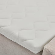 Nahaufnahme einer weißen Matratze mit wellenförmigem Muster auf einem Boxbett.