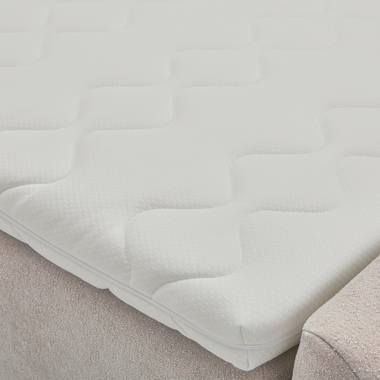 Nahaufnahme einer weißen Matratze mit wellenförmigem Muster auf einem Boxbett.