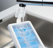 Eiswürfelform CUBO PLUS wird unter einem Wasserhahn befüllt, aus der Vogelperspektive betrachtet.