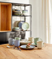 Koffieservies Nature, 18-delig, op een houten tafel, bestaande uit kopjes, schotels en schalen in natuurlijke kleuren, zijaanzicht.