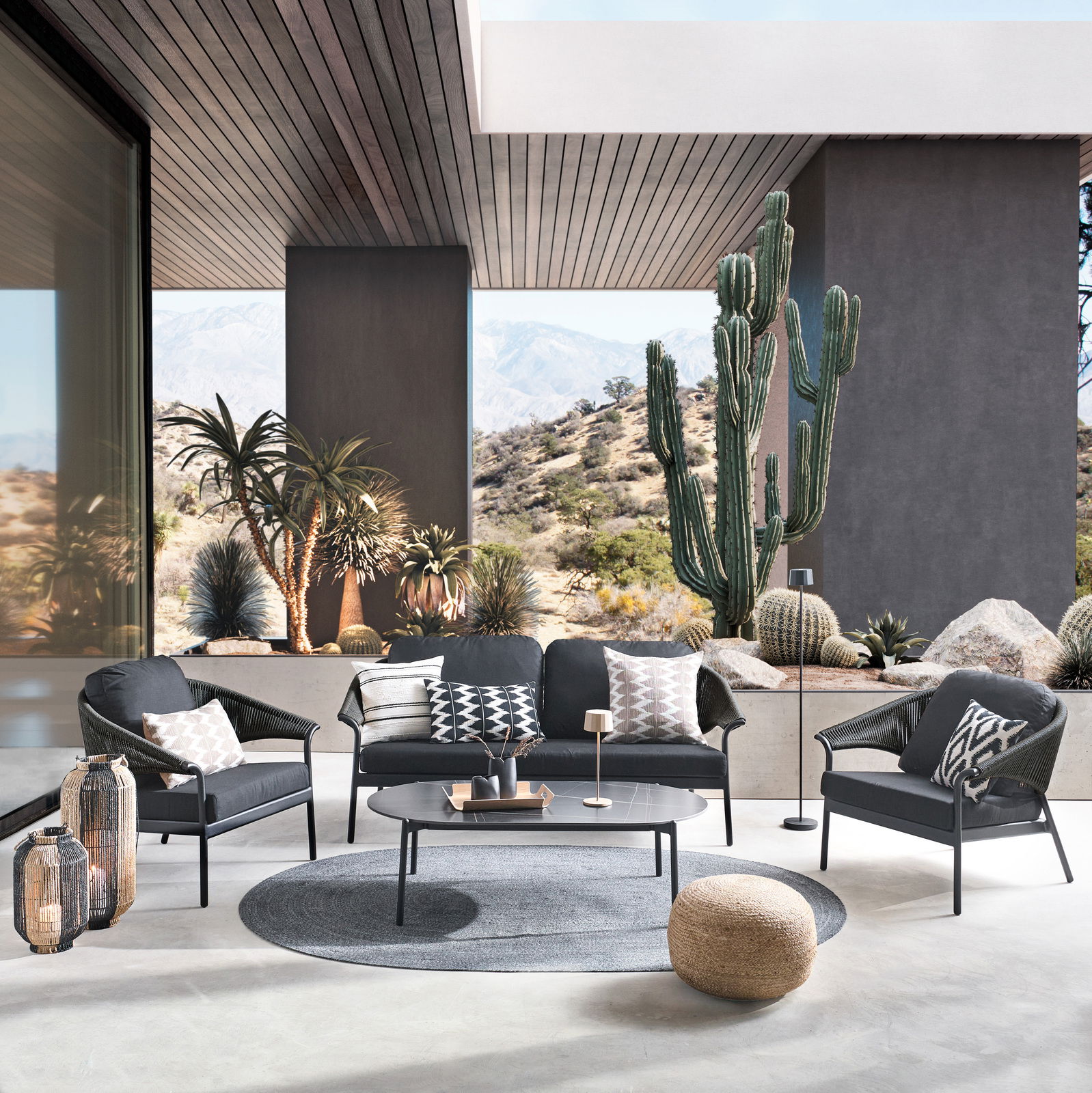 Moderne Loungegarnitur in einem stilvollen Außenbereich mit Wüstenlandschaft im Hintergrund, aus der Perspektive von vorne aufgenommen.