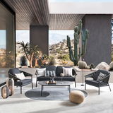 Moderne Loungegarnitur in einem stilvollen Außenbereich mit Wüstenlandschaft im Hintergrund, aus der Perspektive von vorne aufgenommen.