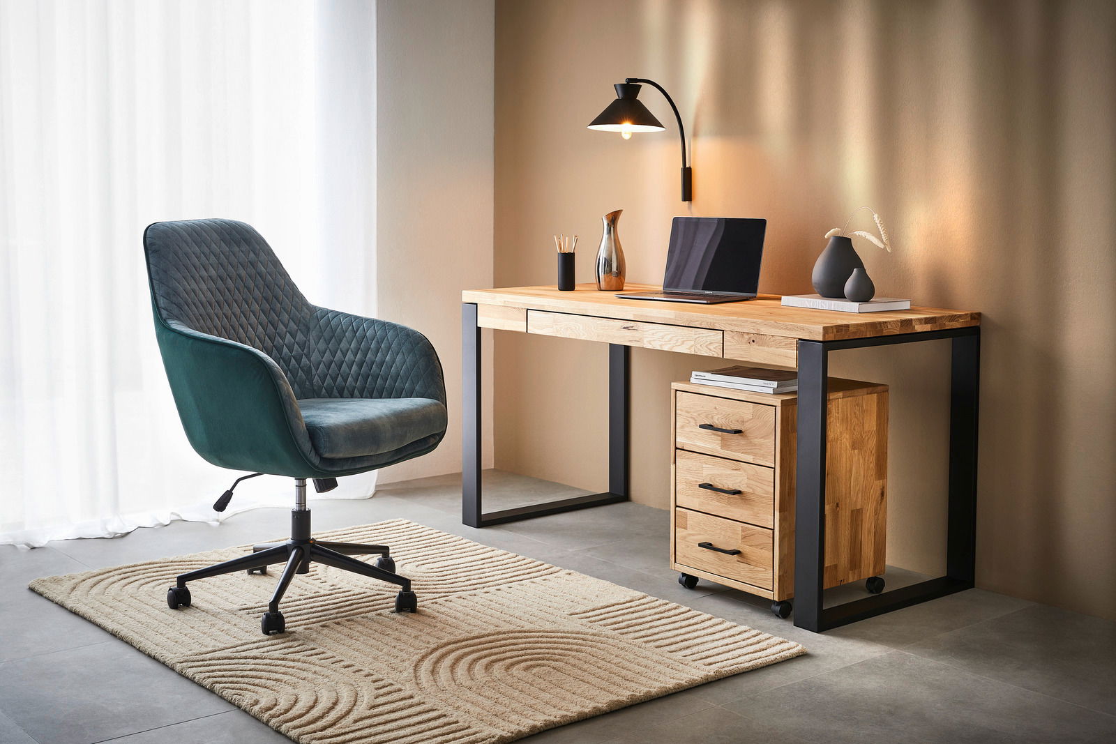 Moderner Schreibtisch aus Holz mit schwarzem Metallrahmen, seitlich betrachtet. Der Schreibtisch ist mit einer Lampe, einem Laptop und Dekorationen ausgestattet. Daneben steht ein gepolsterter Bürostuhl auf einem Teppich.