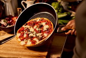 Een koekenpan met een diameter van 28 cm, met daarin een versgebakken pizza, gezien vanuit een zijdelingse hoek van bovenaf.